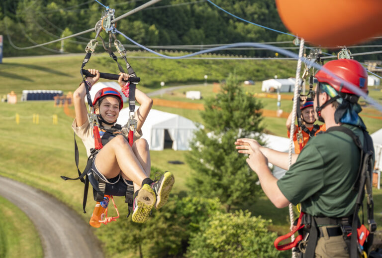 Jamboree scout ziplining over a lush forest environment